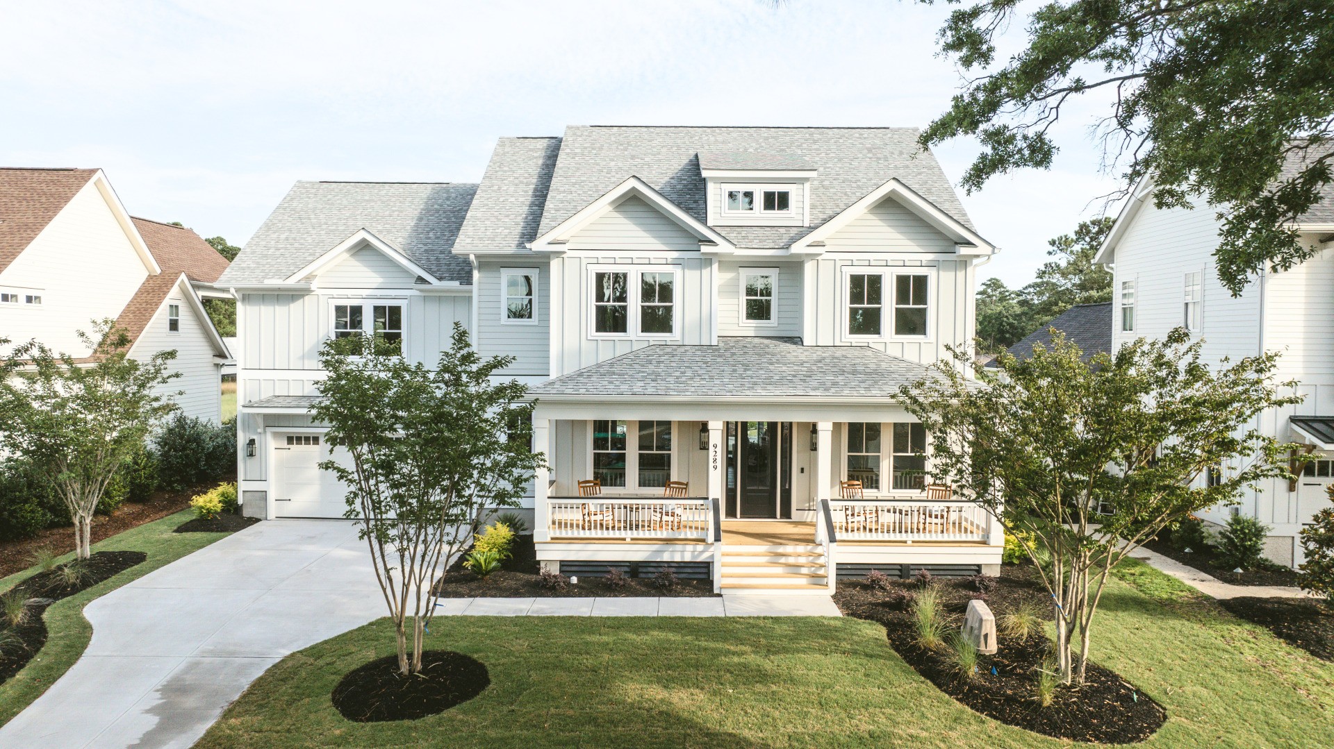 Modern two-story home with a front porch, landscaped yard, and spacious driveway, showcasing home builder craftsmanship.