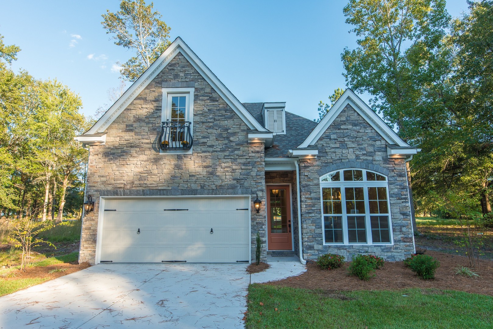 Elegant hallway with brick ceiling, dark wood floor, and white shiplap walls, leading to a glass front door. Designed by a home builder.