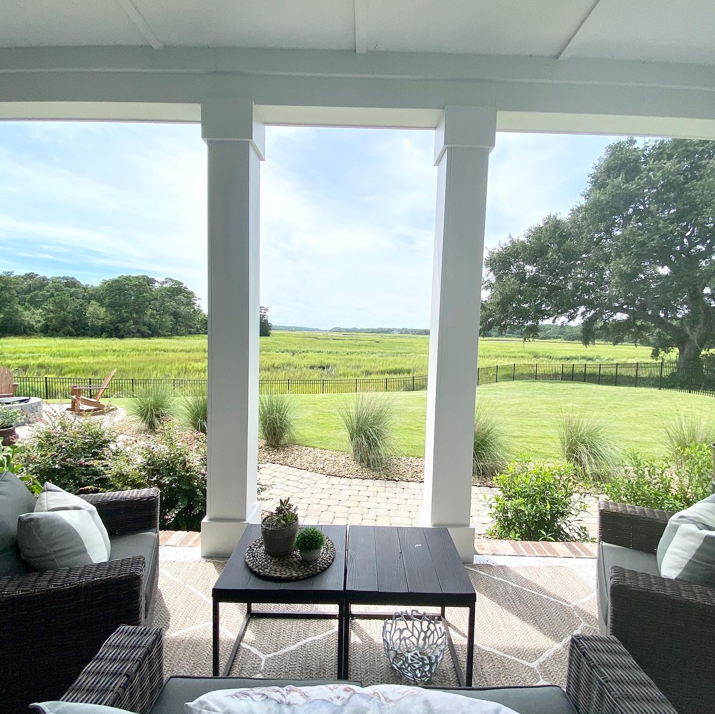 Charming patio view of lush green fields and trees framed by white columns, showcasing home builder's attention to serene outdoor living spaces.