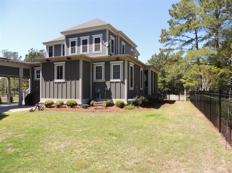 Devaun Park 1- Hallway Elegant hallway with brick ceiling, dark wood floor, and white shiplap walls, leading to a glass front door. Designed by a home builder.