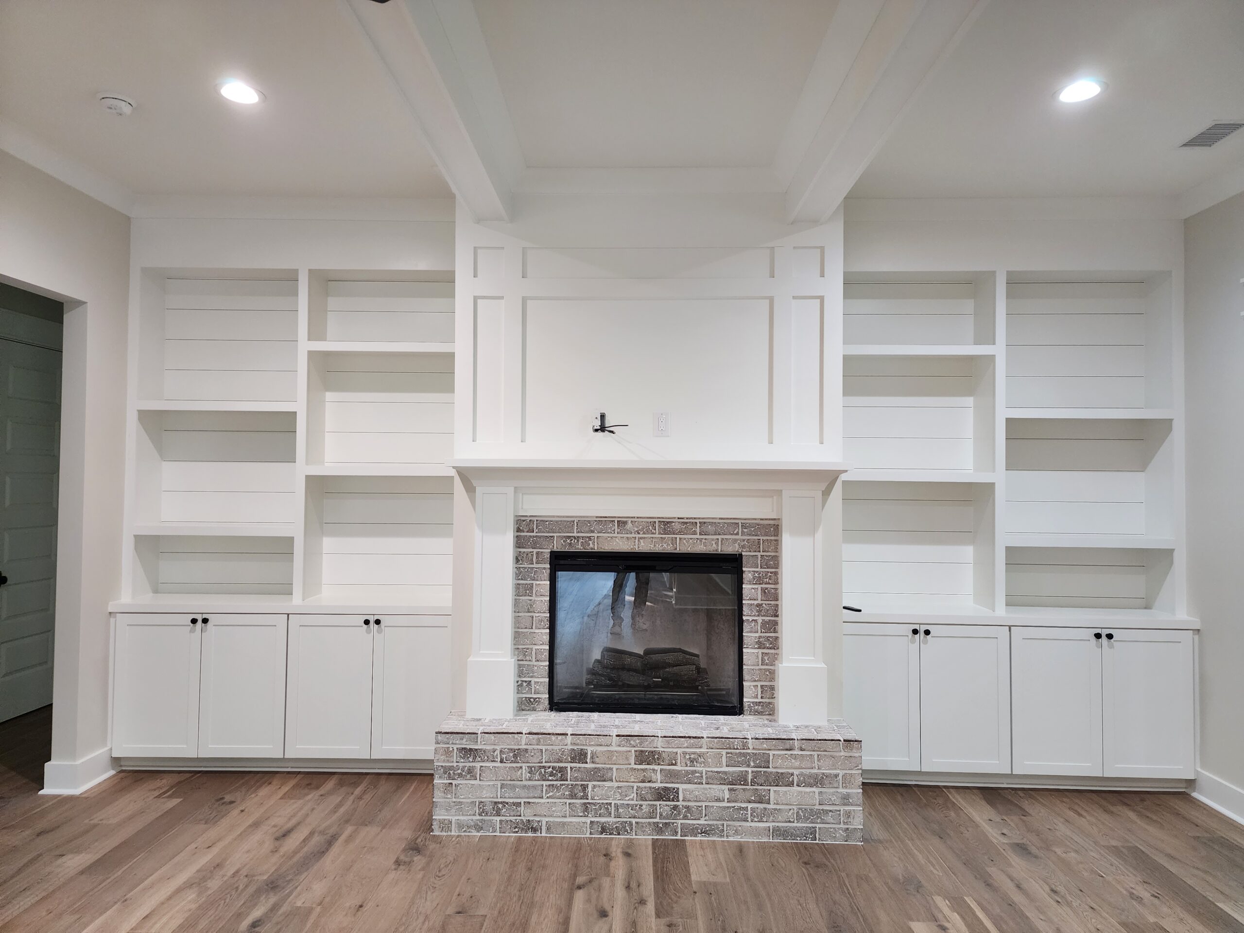 Devaun Park 1- Hallway Elegant hallway with brick ceiling, dark wood floor, and white shiplap walls, leading to a glass front door. Designed by a home builder.