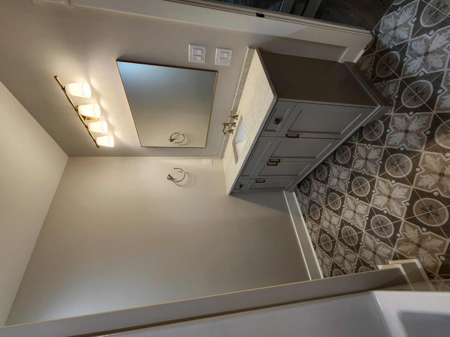 OceanHarbourEstates (7) (Large) Bathroom interior with patterned tile floor, gray vanity with marble countertop, and warm lighting, showcasing home builder craftsmanship.